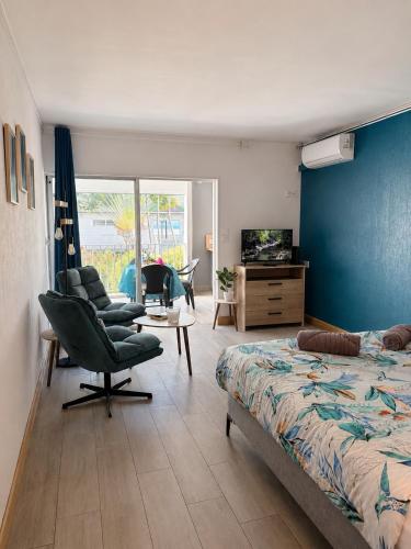 a bedroom with a bed and chairs and a television at Reflet Marin - Studio Village Soleil in Le Gosier