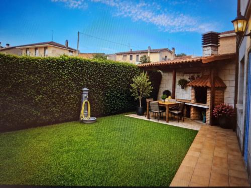 a backyard with a green hedge and a table and chairs at Fuenteazul in Hortigüela
