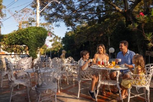a family sitting at a table in a garden at Pousada Estalagem de Brotas in Brotas