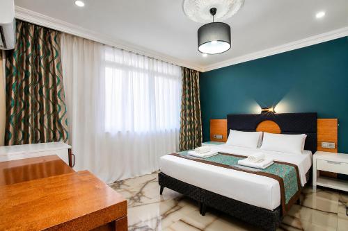 a bedroom with a large bed with a blue wall at Dublin Hotel in Alanya