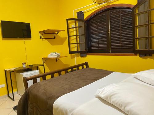 a bedroom with a bed and a yellow wall at Pousada casa amarela Analândia SP in Analândia