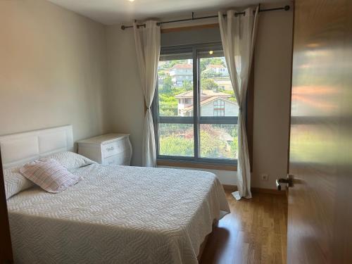 a bedroom with a bed and a large window at Petit con piscina in Pontevedra