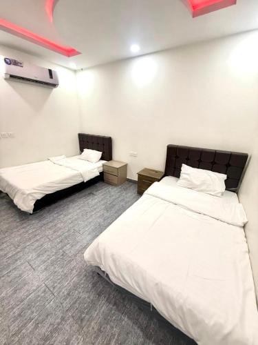 two beds in a room with white walls at شاليهات زارا 2 in Taif