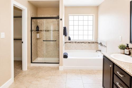 a bathroom with a shower and a tub and a sink at The Palo Pinto in Alamogordo