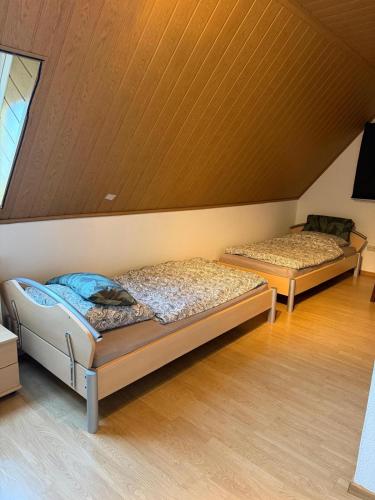 two beds in a room with a wooden ceiling at Wohnen nahe der Ems in Fresenburg