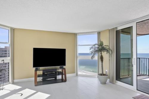 a living room with a flat screen tv and views of the ocean at Two Bedroom Corner Condo with Panoramic Gulf Views in Clearwater Beach
