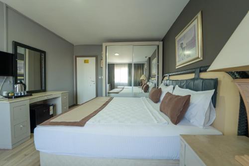 ein großes Schlafzimmer mit einem großen weißen Bett und Spiegeln in der Unterkunft Sever Suites Hotel in Antalya