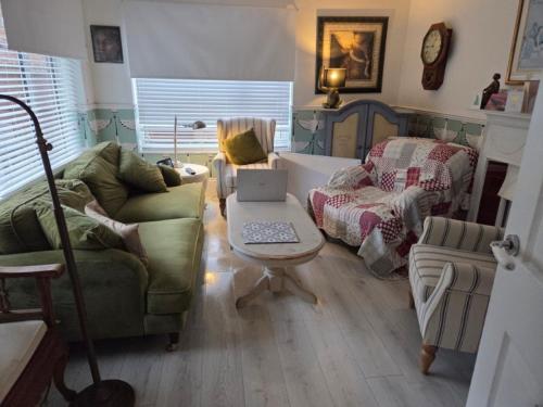 ein Wohnzimmer mit Sofa und einem Tisch mit Laptop in der Unterkunft Firefly Studio in Holt