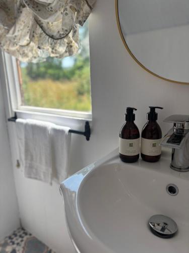a bathroom with a sink with two bottles on it at Blackthorn and Rose Shepherds Huts in Scribbagh