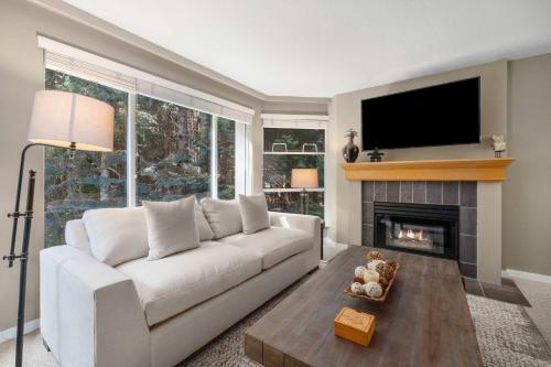 a living room with a white couch and a fireplace at Woodrun Lodge 514 | Ski-In Ski-Out Condo w/ Pool, Hot Tub, Free Parking, Wifi & Laundry in Whistler
