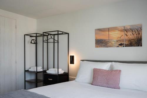 a bedroom with a white bed with a pink pillow at Limen Port View Studio in Tinos