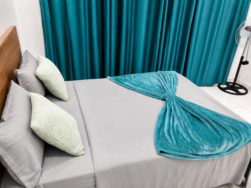 a bed with a blue blanket on top of it at Mags GuestHouse in Praia