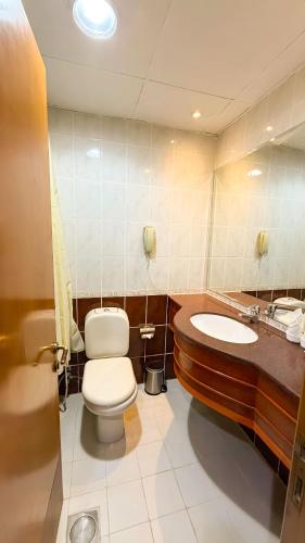 a bathroom with a toilet and a sink and a tub at Elite Jonrad Hotel LLC in Dubai