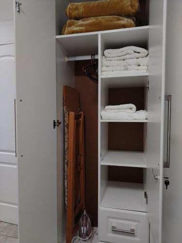 a closet with white shelves and white towels at Eluthando Guesthouse in St Lucia