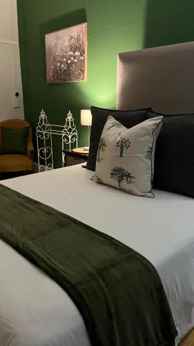 a bed with a black and white pillow and a green wall at Boer & Brit, Graaff-Reinet in Graaff-Reinet
