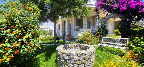 a garden with a bench and flowers in front of a building at Grillo Superior Apartments - Enjoy Your Life! in Capo Vaticano
