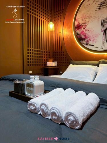 a hotel room with two beds with towels and a tv at Saimer Home in Tân Thành (1)