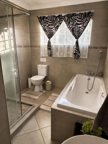 a bathroom with a tub and a toilet and a shower at Galago Rest in Leeupoort