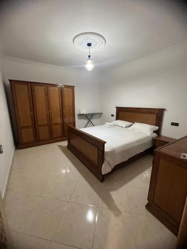 a bedroom with a large bed and wooden cabinets at Atouli Suites in Nador