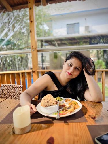 a woman sitting at a table with a plate of food at Bela Blue Stays in Bardez