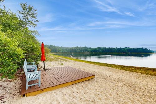 a wooden deck with a chair and an umbrella on a beach at Pond Treasure in Sandwich