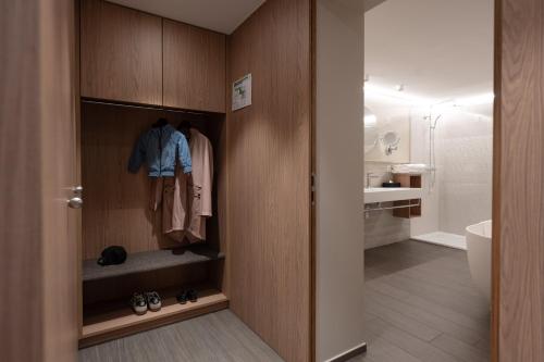 a bathroom with a closet with a robe and a sink at Hotel Safiro in Fluelen