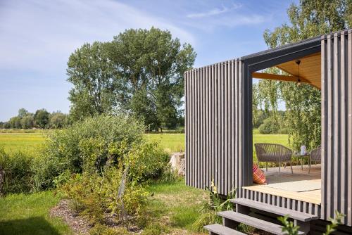 a small house with a glass door and a deck at 110 Tiny House mit traumhaftem Blick über die Wiese in Bleckede