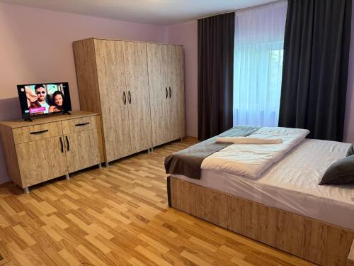 a bedroom with a bed and cabinets and a television at Casa David in Mălăeşti