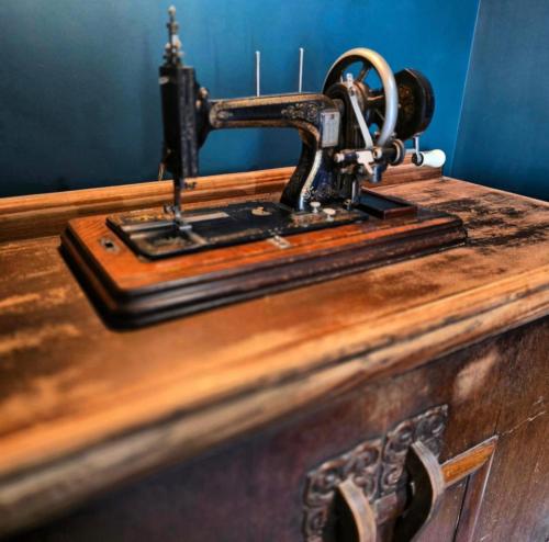 an old sewing machine sitting on top of a wooden table at The Wolf's Den in Patrington