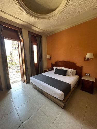 a bedroom with a large bed and a large window at Hotel Santiago De Compostela - Guadalajara Centro Historico in Guadalajara