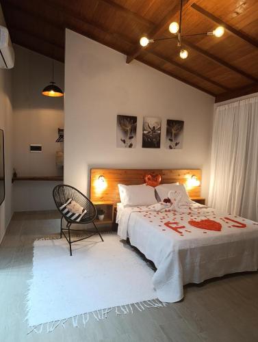 a bedroom with a large bed and a chair at Chalé Recanto da Chiquinha in Santa Teresa