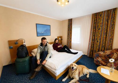a man and a woman sitting on a bed with a dog at Garden Depandance Am Bach in Kurort Altenberg