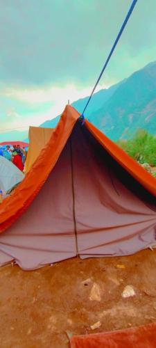 a red and orange tent sitting on the ground at Glacier view point kedarnath in Kedārnāth