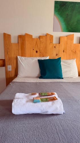 a bed with a wooden headboard with a towel on it at Pousada Bouganvile Atins in Atins