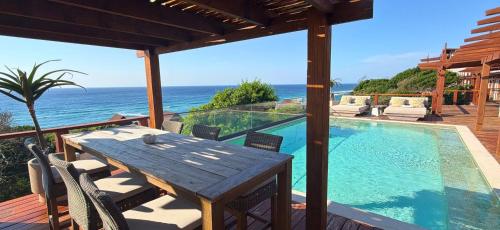a patio with a wooden table and a swimming pool at Aloha 28 in Ponta Mamoli