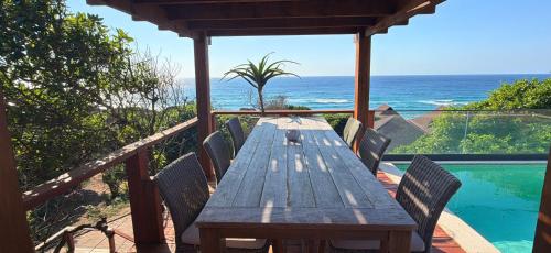a wooden table on a deck with a view of the ocean at Aloha 28 in Ponta Mamoli