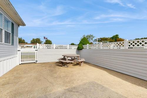 a patio with a picnic table next to a white fence at Assateague Point - Bay Breeze in Berlin