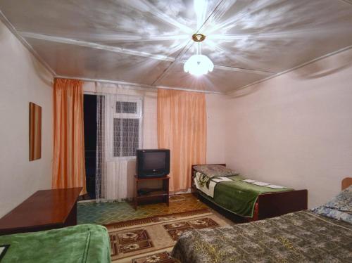 a room with two beds and a tv in it at Valentina`s Guesthouse in Korumdy