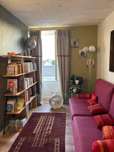 a living room with a purple couch and a book shelf at L'Olivier in Charron