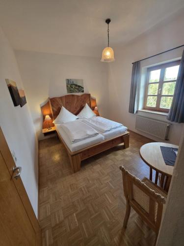 a bedroom with a bed and a table and a window at Zum Schlosswirt in Fürsteneck