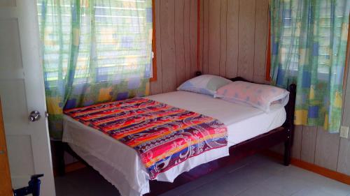 a small bedroom with a bed with a colorful blanket on it at Don Santiago Guesthouse Downtown in San Ignacio