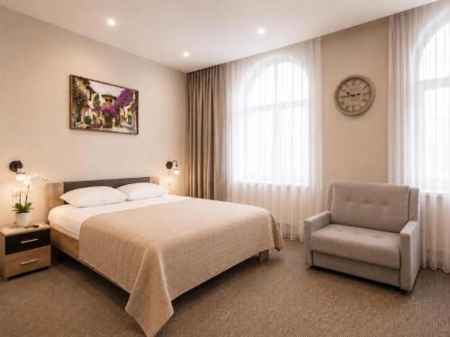 a bedroom with a bed and a chair and a clock at Nika Apart hotel in Riga