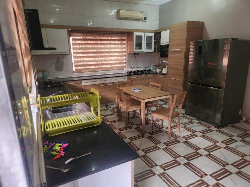a kitchen with a table and chairs and a refrigerator at Afiraiserviceapartment in Kaduna