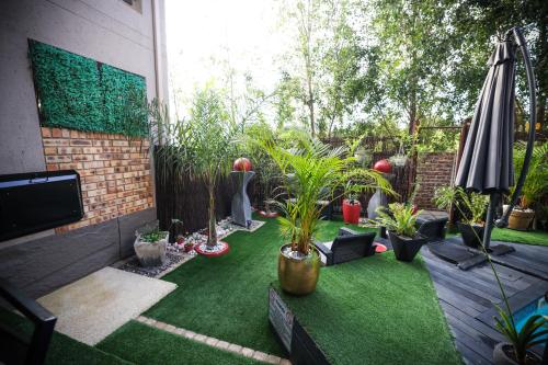 a small garden with plants and an umbrella at Heated Pool Luxury Retreat - 7 Min from OR Tambo in Benoni