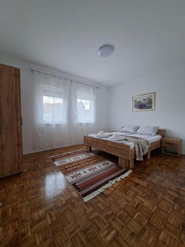 a white room with a bed and a rug at Apartmani E&A Jasmina Okanović in Gradačac
