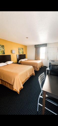 a hotel room with two beds and a chair at ORO North Beach Inn in Corpus Christi
