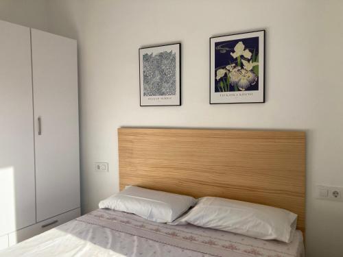 a bedroom with a wooden headboard and two pictures on the wall at Caliu Tremp in Tremp