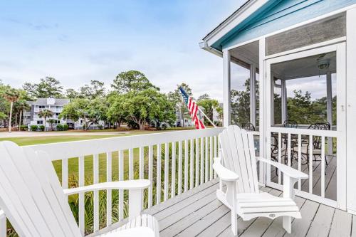 a porch with two white chairs and an american flag at Heh Edisto in Edisto Beach
