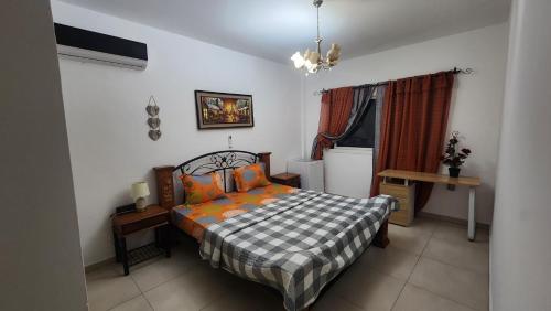 a bedroom with a bed and a table and a window at Appart Bougainvillier in Libreville