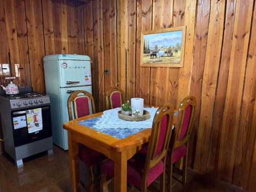 a kitchen with a table with chairs and a refrigerator at Refugio Barbara Coñaripe in Coñaripe
